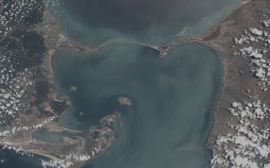 Satellite view of a shallow coastal strait with sediment plumes.